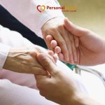 Caregiver holding an elderly patient's hands during hospice care at home