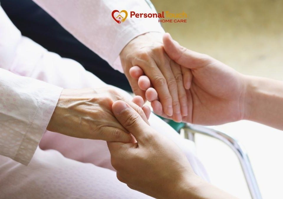 Caregiver holding an elderly patient's hands during hospice care at home