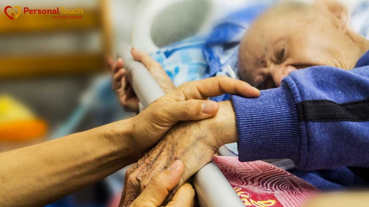 Caregiver holding the hand of an elderly veteran receiving VA hospice care at home