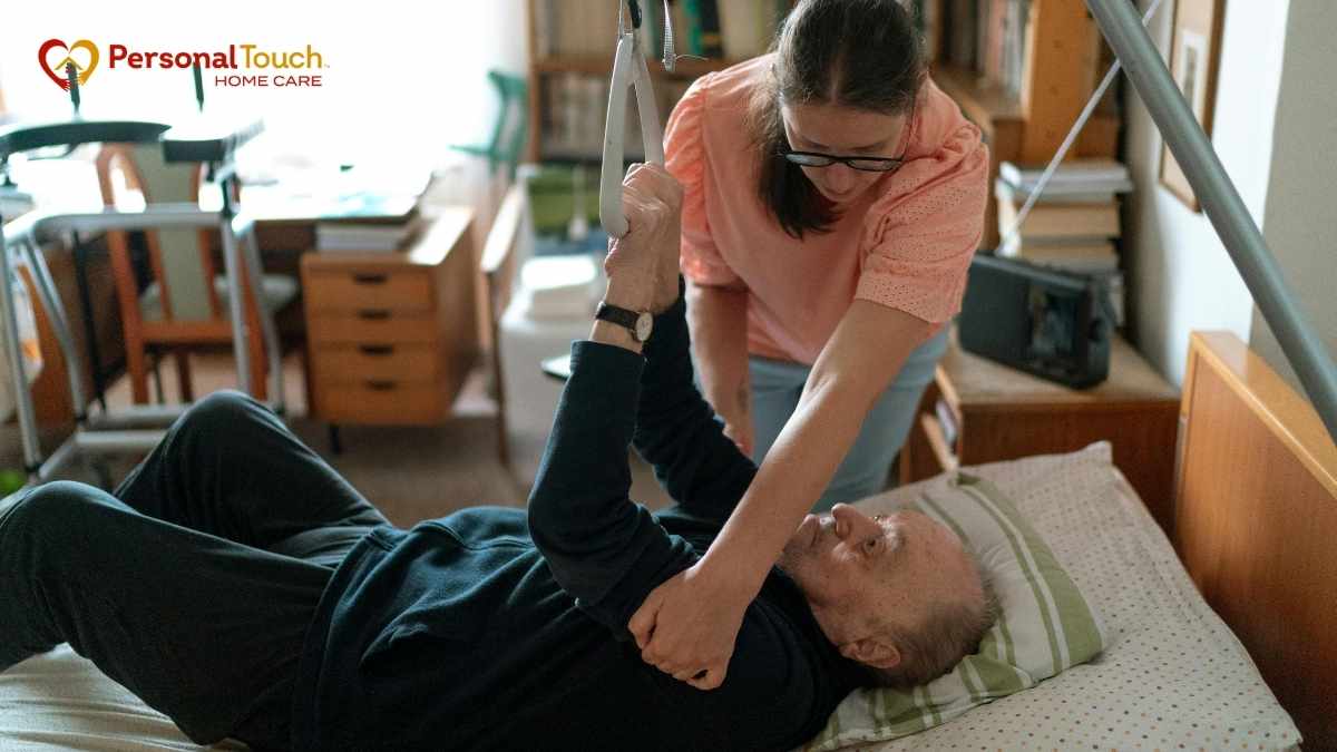 Home caregiver helping an elderly man sit up in bed at home
