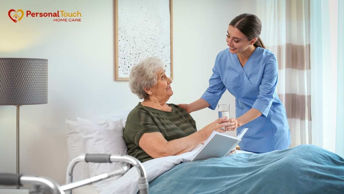 Nurse handing a glass of water to an elderly woman resting in bed at home