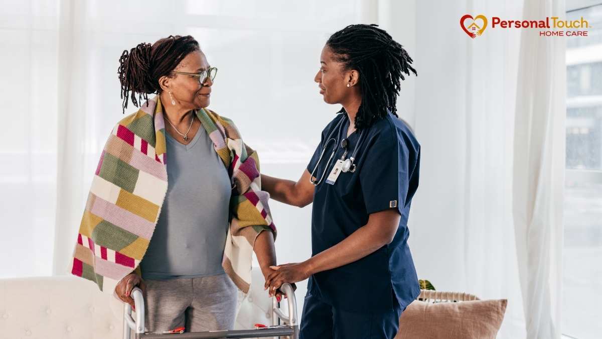 Nurse with stethoscope supporting an elderly woman using a walker at home